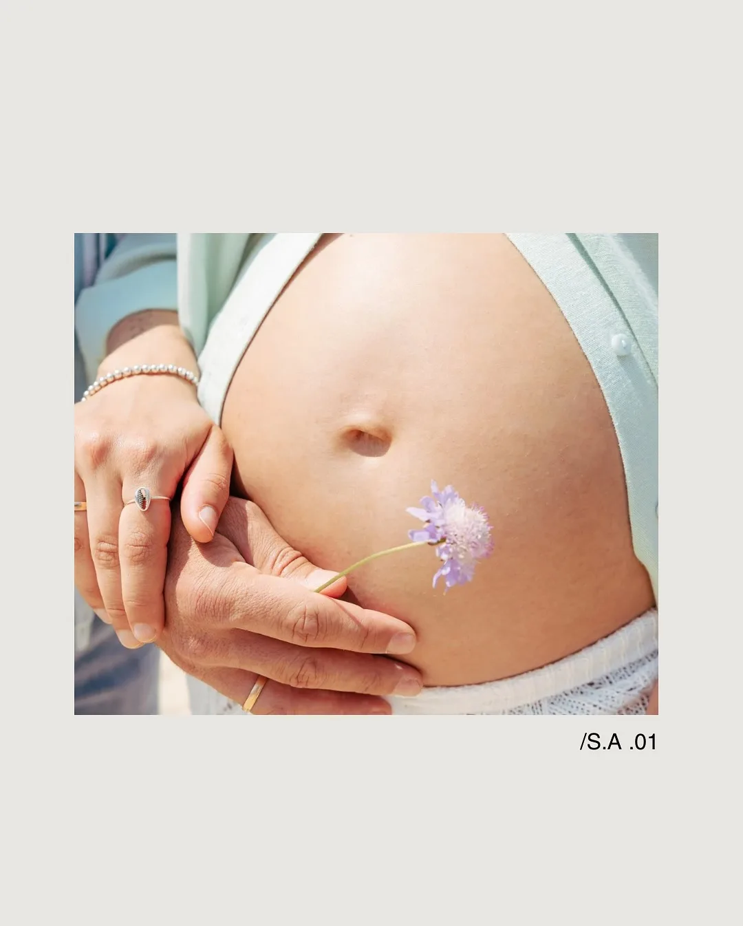 Detalle íntimo de una sesión de maternidad con flor